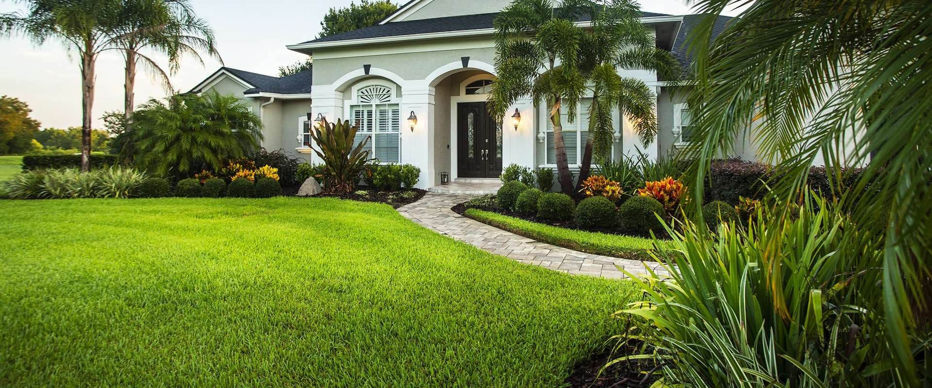 Palm Beach County home with a manicured lawn and tropical landscaping