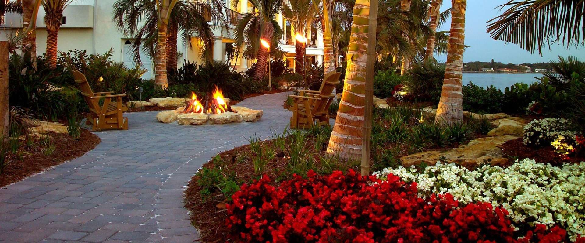 Landscaped walkway with fire pit, palms and flowering beds